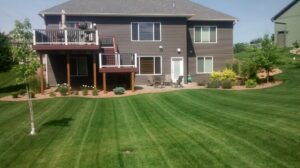 A well-maintained backyard with a mowed lawn and patio area, expertly cared for by Three Boys Lawncare in Rochester, MN.