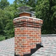A well-maintained brick chimney with a protective cap on a roof, serviced by Al's Chimney Sweep in Pittsburgh, PA.