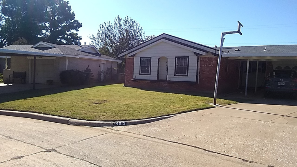 A well-maintained front lawn of a house on a corner lot by Cunningham Kyngz Lawn Care in Oklahoma City, OK
