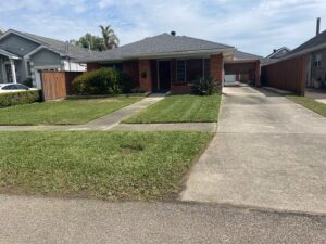 A residential front yard with a neatly mowed lawn and clean driveway, maintained by God's Sight Lawn & Gardens LLC in New Orleans, LA