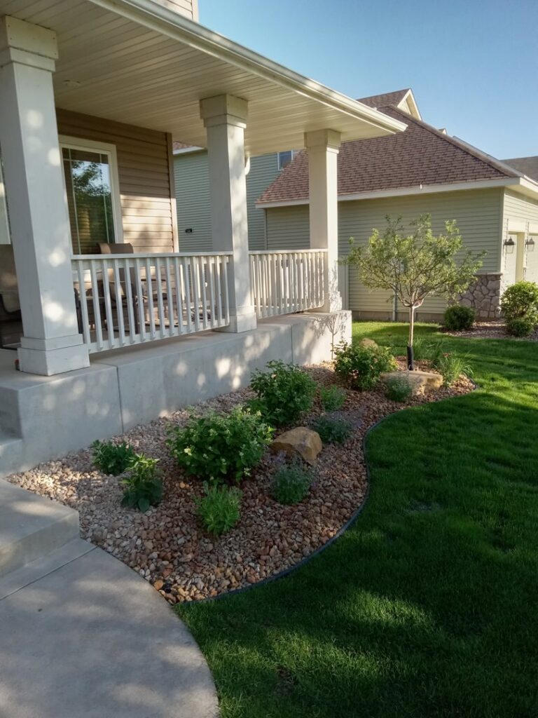 A beautifully well-maintained front lawn and landscaped garden bed, showcasing the quality work of Nice Grass Minnesota LLC in Minneapolis, MN.