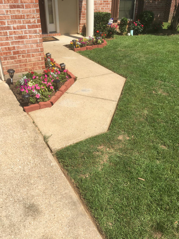 A beautifully maintained lawn and vibrant flowerbeds along a walkway, showcasing services by Taylor Cutts lawn Care Service llc in Shreveport, LA