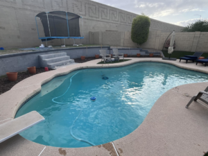 A well-maintained blue swimming pool with a pool cleaner operating, demonstrating the service of Brigade Pool Services in Tempe, AZ.