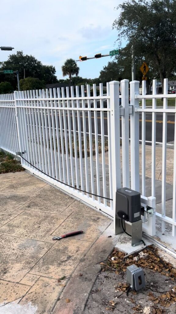A white aluminum automatic sliding gate with an opener for secure property access by ARE FENCE LLC in Miami, FL.