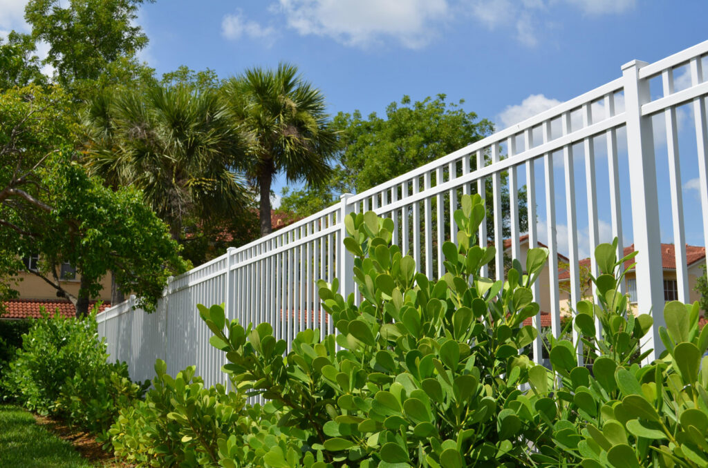 A white aluminum fence installed with lush greenery in front by Best Fence and Rail in Jacksonville, FL.