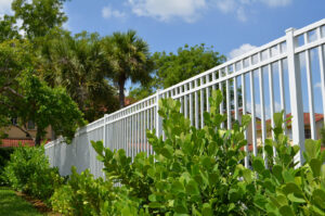A white aluminum fence installed with lush greenery in front by Best Fence and Rail in Jacksonville, FL.