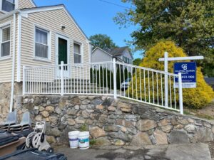 Custom white aluminum railings installed along a stone wall in front of a home by AVA Fence & Railing LLC in Stamford, CT.