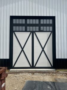 A white barn-style garage door with a black cross-buck design and windows, installed by Steve's Overhead Door Company in Lafayette, IN.