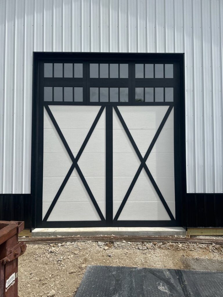 A white barn-style garage door with a black cross-buck design and windows, installed by Steve's Overhead Door Company in Lafayette, IN.