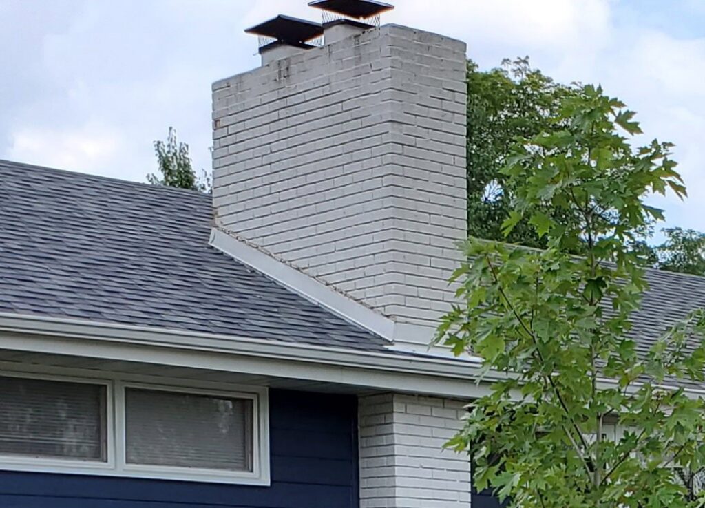 A white brick chimney with two new caps, showcasing work by JJ Chimney Services in Minneapolis, MN.