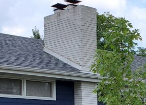 A white brick chimney with two new caps, showcasing work by JJ Chimney Services in Minneapolis, MN.