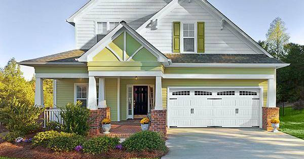 A beautiful light green house featuring a new white carriage-style garage door installed by Frankfort Overhead door Sales & Service in Frankfort, KY