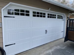 A white carriage-style garage door with decorative hardware and windows installed by Independent Garage Doors LLC in Tacoma, WA.