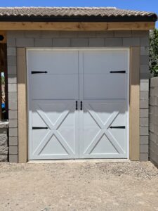 A newly installed white carriage-style garage door with decorative hardware by Tucson Garage Door Doc in Tucson, AZ.