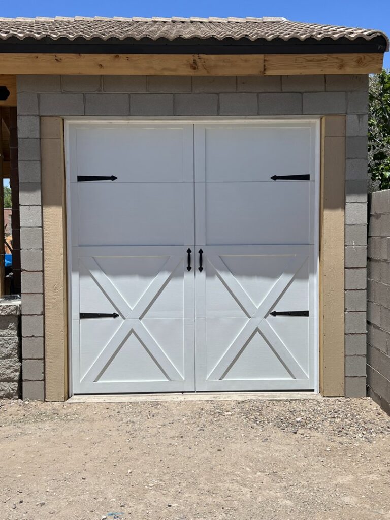 A newly installed white carriage-style garage door with decorative hardware by Tucson Garage Door Doc in Tucson, AZ.