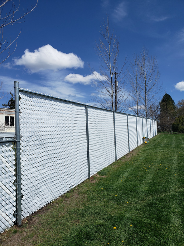 A long white chain-link fence with privacy slats installed by Big Canyon Fencing in Lewiston, ID.