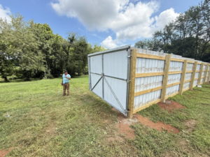 A white corrugated metal fence with sturdy wooden posts and a large gate by JV Fences in Lexington, KY.