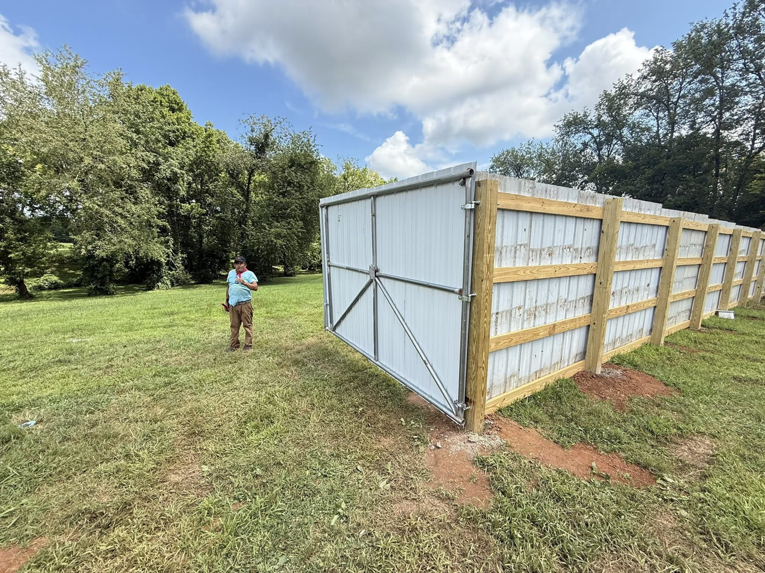 A white corrugated metal fence with sturdy wooden posts and a large gate by JV Fences in Lexington, KY.
