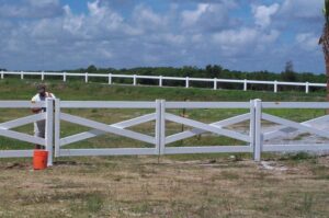 A white cross-buck style farm fence with a gate installed by Nash Fence & Supplies Inc. in Lake Charles, LA.