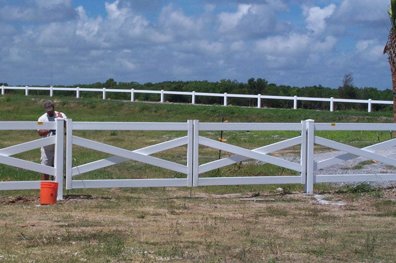 A white cross-buck style farm fence with a gate installed by Nash Fence & Supplies Inc. in Lake Charles, LA.