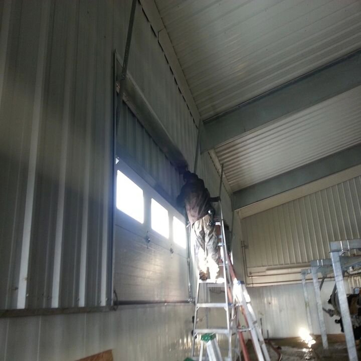 A close-up of a newly installed white garage door with decorative windows and hardware by American Eagle Garage Doors in Greeley, CO.