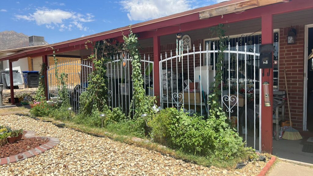 A white decorative metal fence with ornate details by Iron Man Exteriors in Las Cruces, NM.
