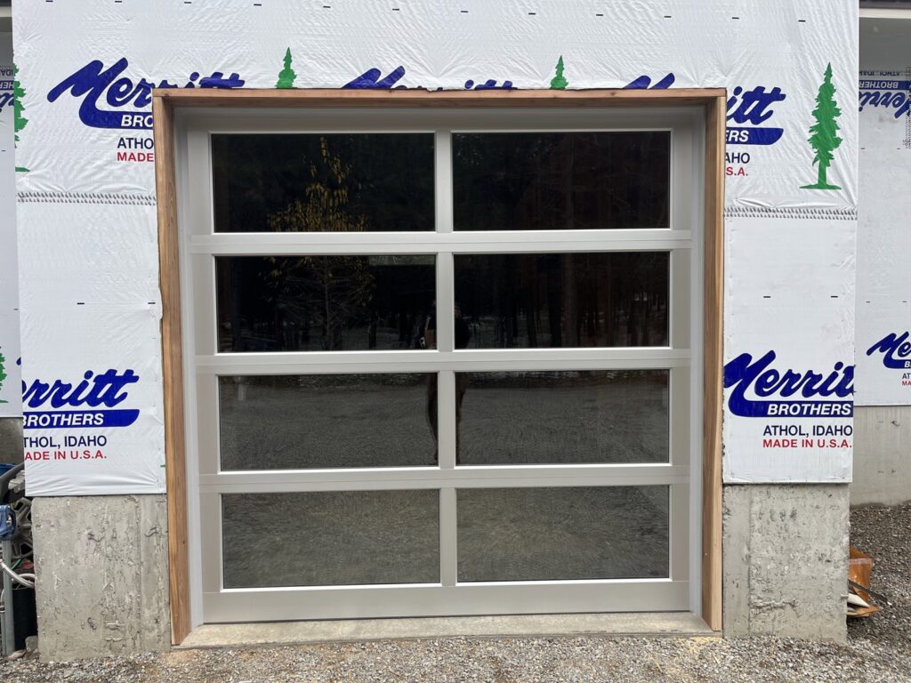 A modern white full-view glass garage door installed on a new construction by Remarkable Door Company in Spokane, WA.