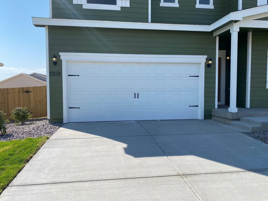 A white garage door with decorative black hardware installed by Strongdoor garage in Denver, CO.