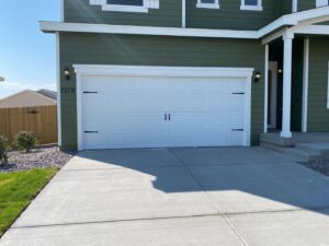 A white garage door with decorative black hardware installed by Strongdoor garage in Denver, CO.
