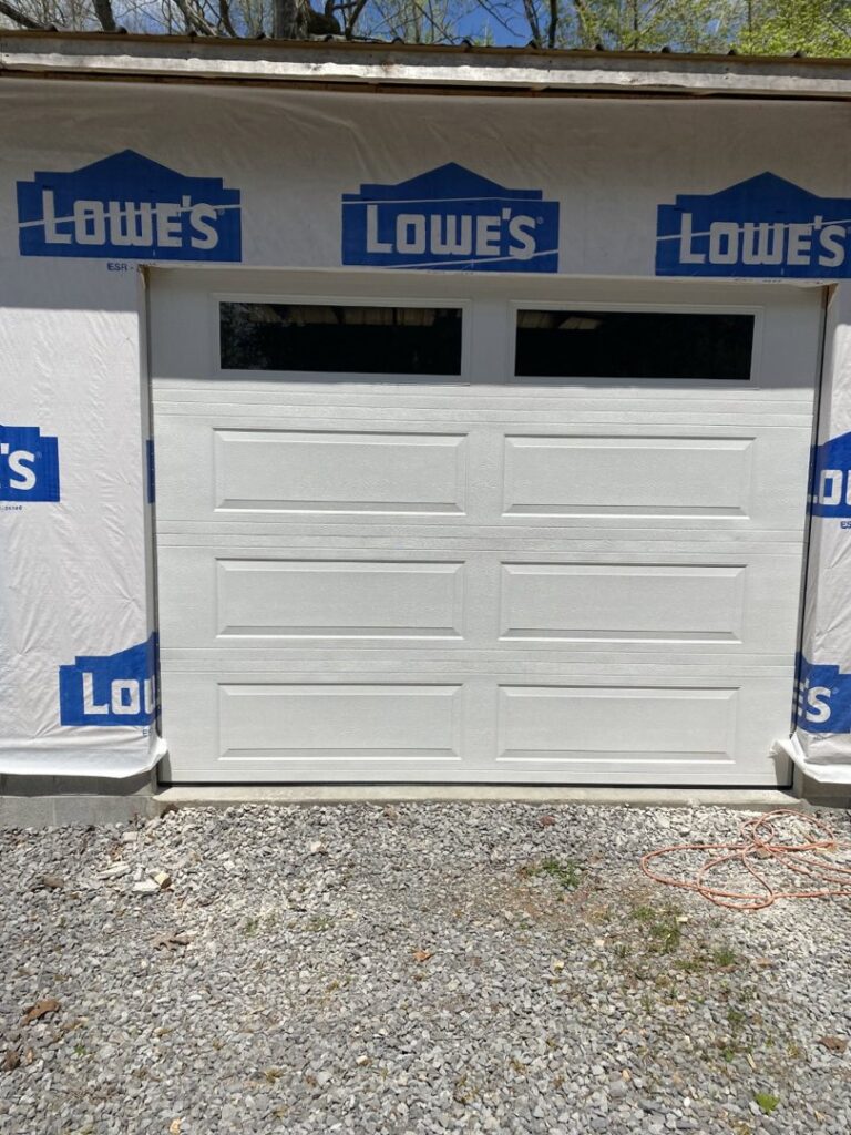 A white panel garage door newly installed on a house under construction by Smith's Garage Door in Clarksville, TN.