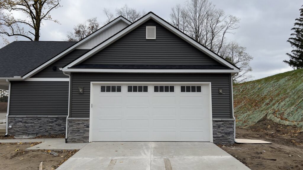 New white garage door with windows installed on a home with dark siding by Superior Overhead Door, LLC in Granger, IN