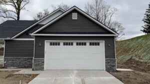 New white garage door with windows installed on a home with dark siding by Superior Overhead Door, LLC in Granger, IN
