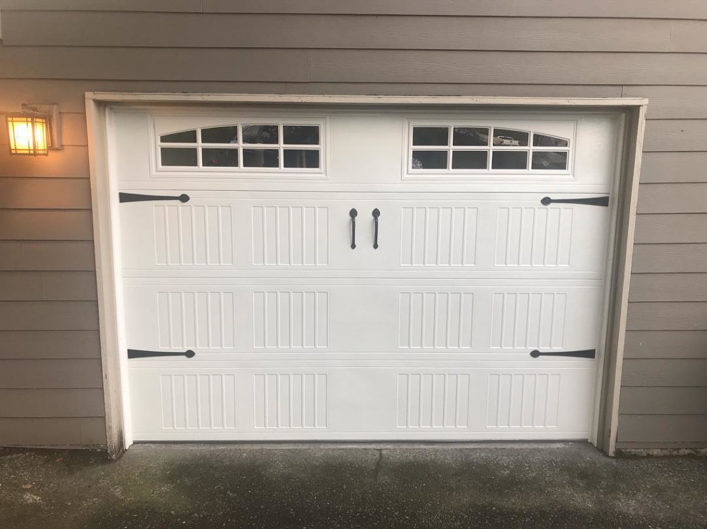 A newly installed white garage door with decorative hardware by Discount Garage Door Company in Spokane, WA.