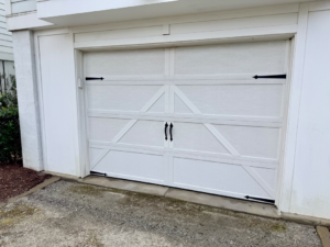 A newly installed white garage door with decorative hardware by On Track Garage Doors in Charleston, SC.