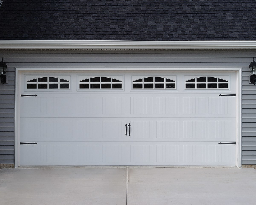 A newly installed white garage door with decorative windows and hardware by Phildor Construction in Aurora, CO
