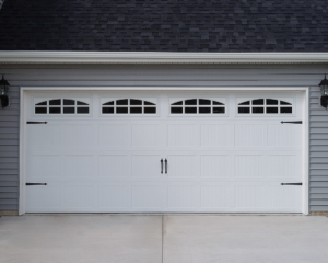 A newly installed white garage door with decorative windows and hardware by Phildor Construction in Aurora, CO