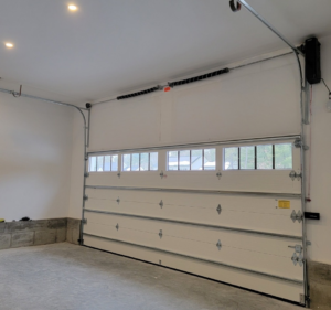 Interior view of a newly installed white garage door with windows, tracks, and opener by Southcoast Overhead Door & Services in Fall River, MA.