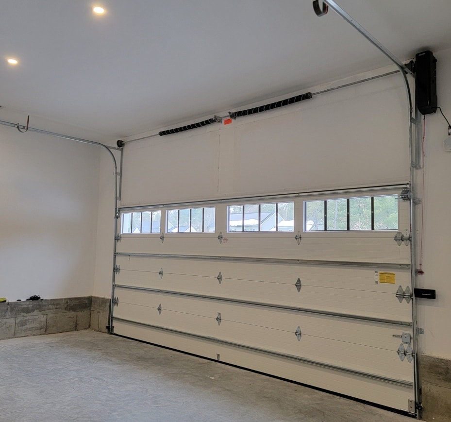 Interior view of a newly installed white garage door with windows, tracks, and opener by Southcoast Overhead Door & Services in Fall River, MA.