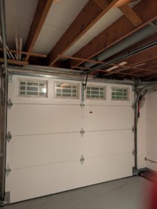 A newly installed white garage door with its opener mechanism by Gilliam Services LLC in Johnson City, TN.