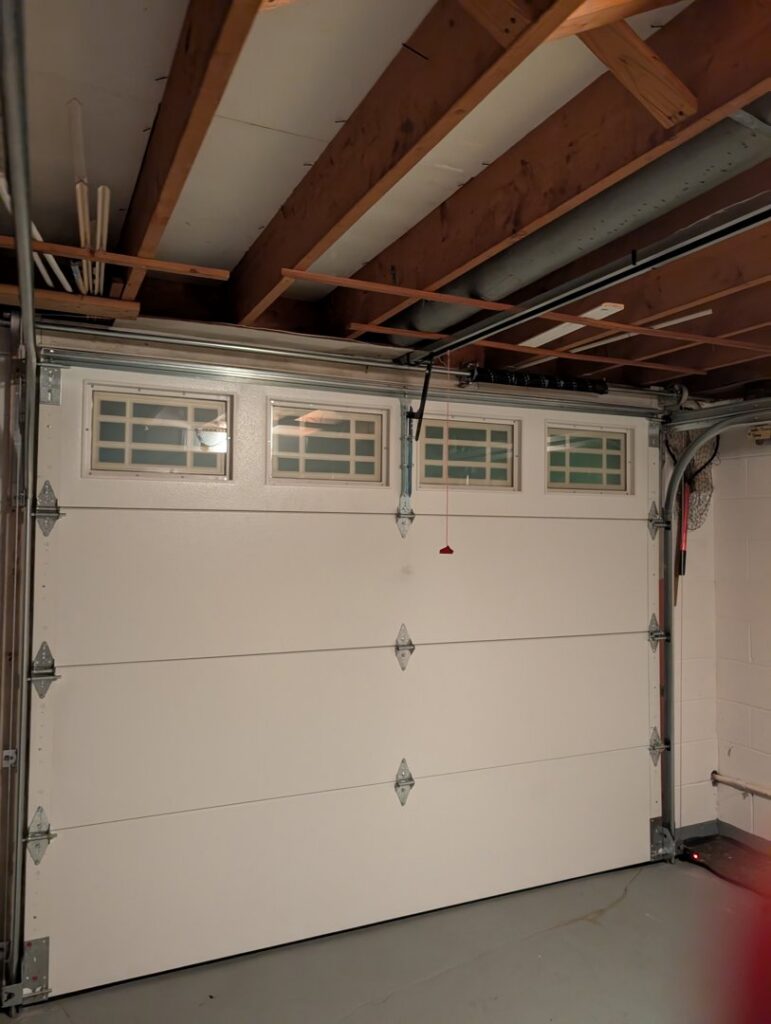 A newly installed white garage door with its opener mechanism by Gilliam Services LLC in Johnson City, TN.