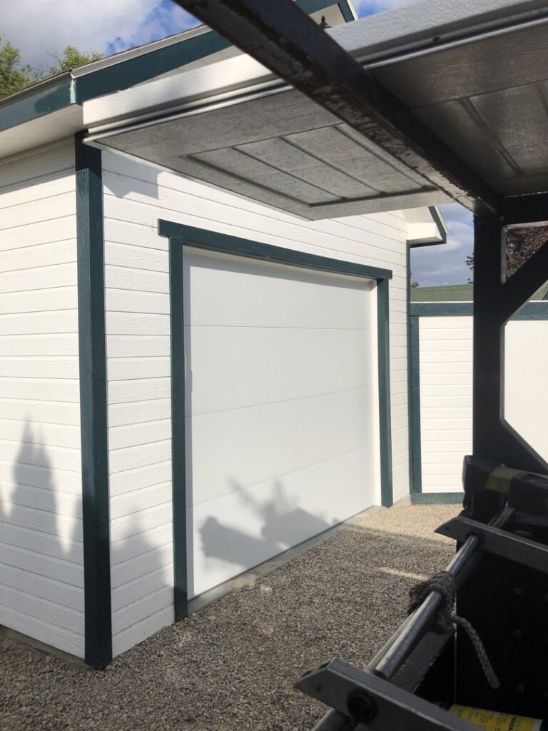 A newly installed white garage door on an outbuilding by Colorado Garage Door Guy in Aurora, CO.