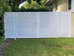 A modern white horizontal slat fence with a gate installed by Palm's Fence of Miami, FL.
