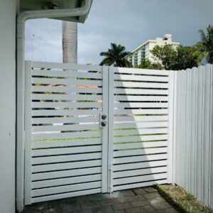 A white horizontal slat gate next to a corrugated metal fence installed by Miami Fence Installation Contractors in Miami, FL.