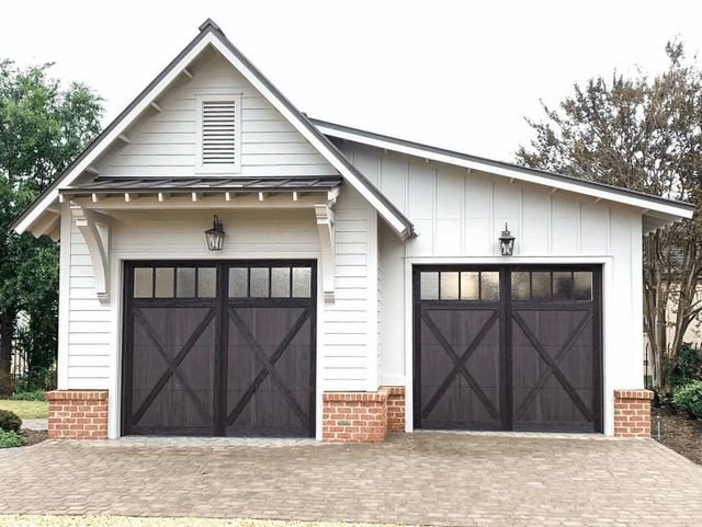 A charming white house with two dark brown carriage-style garage doors installed by Monroe Overhead Doors in Monroe, LA.