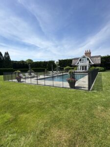 A white mesh pool safety fence with a self-closing gate installed around a residential pool by Pool Guard in North Charleston, SC.