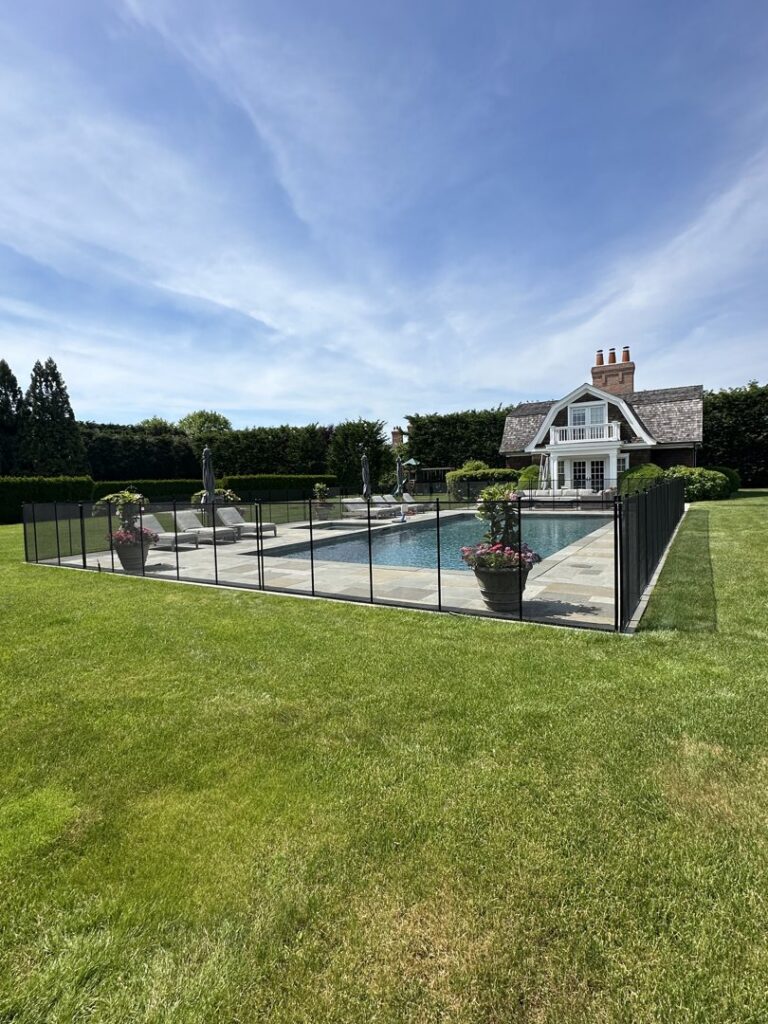 A white mesh pool safety fence with a self-closing gate installed around a residential pool by Pool Guard in North Charleston, SC.