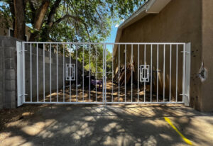 A white metal driveway gate with decorative geometric panels, installed by City Iron LLC in Albuquerque, NM.