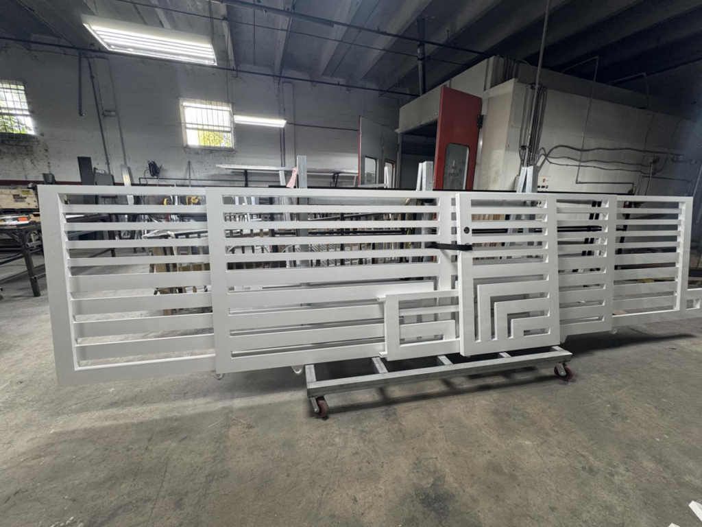 A large white metal sliding gate being fabricated in a workshop by HD Multi Service USA INC in Miami, FL.