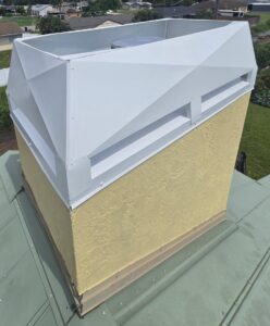 A white modern chimney cap installed on a yellow stucco chimney by SWFL Chimney Caps Inc. in Fort Myers, FL.