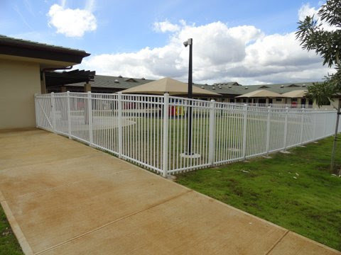 A white ornamental aluminum fence enclosing a grassy area, installed by David's Fencing Inc. in Waipahu, HI.